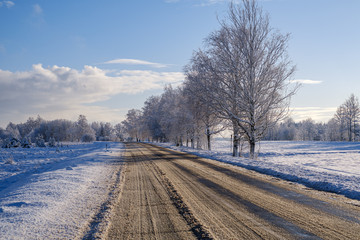 car tracks in the snow on the winter road in sunny day