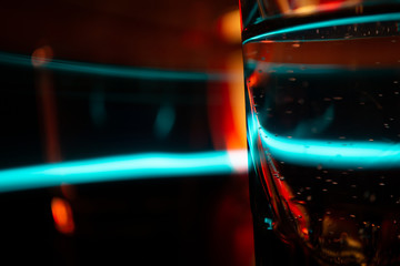 Night Bar Counter Scene with neon lights. Glasses reflected on the surface of the bar. Focus on front glass and blurred background.