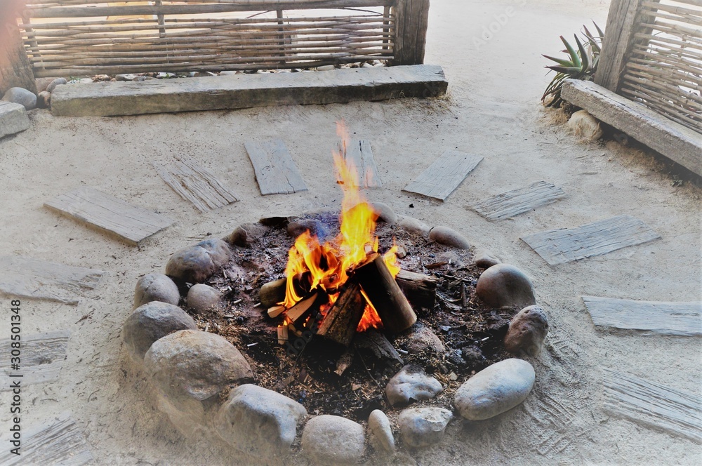 Wall mural Beautiful high angle shot of a burning bonfire surrounded by sand wood and stones