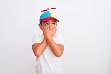 Beautiful kid boy wearing fanny colorful cap with propeller over isolated white background shocked covering mouth with hands for mistake. Secret concept. © Krakenimages.com