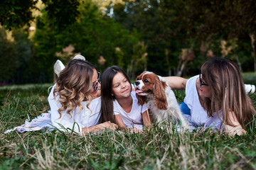 Two young blond women and one brunette girl, wearing white t-shirts, lying on mexican blanket on...