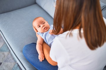 Young beautifull woman and her baby on the sofa at home. Newborn and mother relaxing and resting comfortable