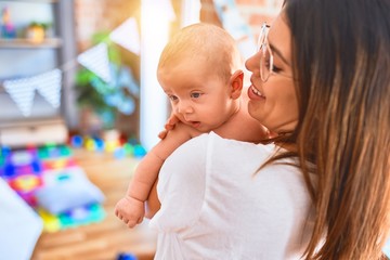 Young beautifull woman and her baby standing at home. Mother holding and hugging newborn