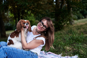 Young blond woman, wearing blue jeans and white t-shirt, sitting on mexican blanket, holding small...