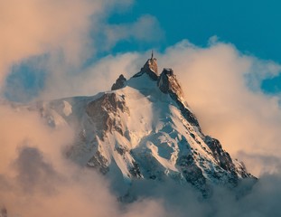 Picture of Aiguille du Midi covered in the snow and the fog under a blue sky in the French Alps