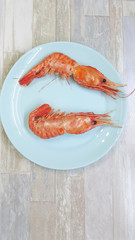 Fresh and tasty boiled wild king prawns with on plate ready for eating. Big red shrimps.