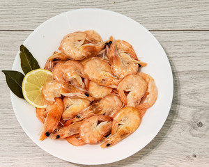 Shrimp on a white plate with lemon. Seafood. Shrimp on a plate, isolated on a gray background.