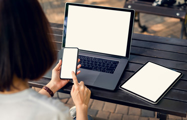 Woman holding smartphone and tablet screen blank with laptop on the table mock up to promote your products.