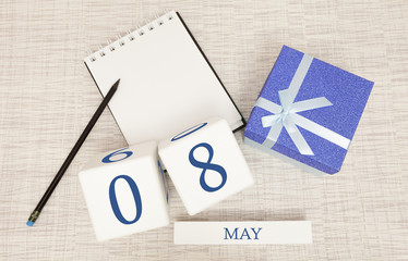 Calendar with trendy blue text and numbers for May 8 and a gift in a box.