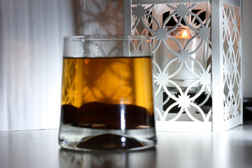 Candle in a decorative lamp over a glass with dried fruit compote