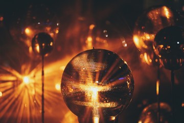 Closeup of a small disco ball under red lights surrounded by disco balls with a blurry background
