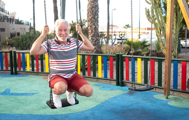 One senior man with white hair plays in the public park with children's games. Outdoor in a...