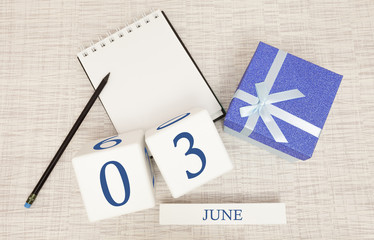 Calendar with trendy blue text and numbers for June 3 and a gift in a box.