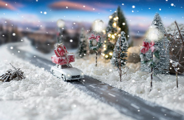 Miniature classic car carrying a christmas gifts on snowy winter landscape - Powered by Adobe