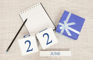 Calendar with trendy blue text and numbers for June 22 and a gift in a box.