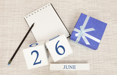 Calendar with trendy blue text and numbers for June 26 and a gift in a box.
