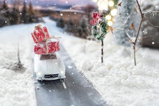 Miniature Classic Car Carrying A Christmas Gifts On Winter Landscape