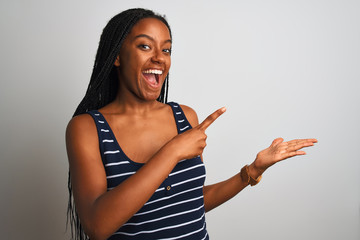 Young african american woman wearing striped t-shirt standing over isolated white background amazed and smiling to the camera while presenting with hand and pointing with finger.