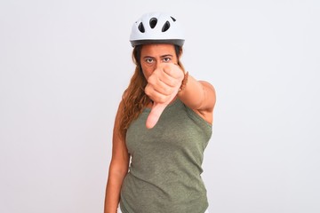 Middle age mature cyclist woman wearing safety helmet over isolated background looking unhappy and angry showing rejection and negative with thumbs down gesture. Bad expression.