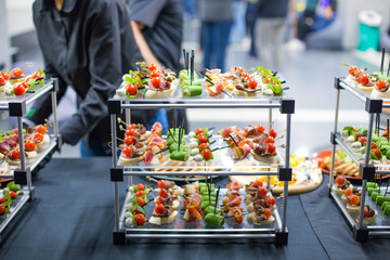 Different canapes with smoked salmon, cucumber, tomatoes, cheese, meat. Breakfast buffet table with...