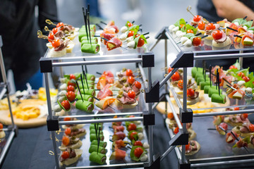 Different canapes with smoked salmon, cucumber, tomatoes, cheese, meat. Breakfast buffet table with...