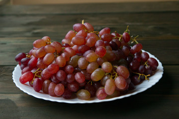 pink grapes on a white plate on a wooden table