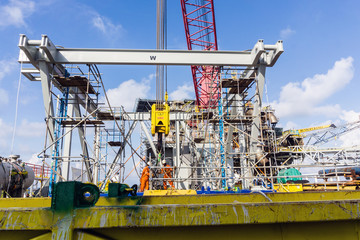 Offshore workers performing inspection to a crane hook and rigging arrangement prior to heavy lift