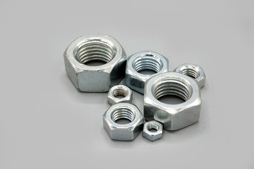 Metal nuts isolated on gray background. New and shiny chrome nuts. Copy space.
