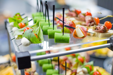 Different canapes with smoked salmon, cucumber, tomatoes, cheese, meat. Breakfast buffet table with a variety of snacks. Buffet served table with snacks,fruits, canape, sweets and appetizers