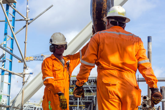Offshore workers performing inspection to a crane hook and rigging arrangement prior to heavy lift