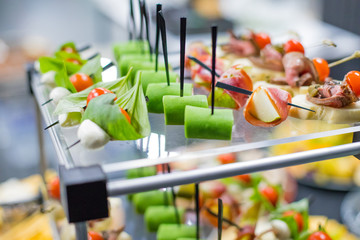 Different canapes with smoked salmon, cucumber, tomatoes, cheese, meat. Breakfast buffet table with a variety of snacks. Buffet served table with snacks,fruits, canape, sweets and appetizers