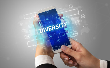 Female hand typing on smartphone with DIVERSITY inscription, social media concept
