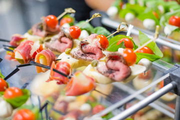 Different canapes with smoked salmon, cucumber, tomatoes, cheese, meat. Breakfast buffet table with a variety of snacks. Buffet served table with snacks,fruits, canape, sweets and appetizers