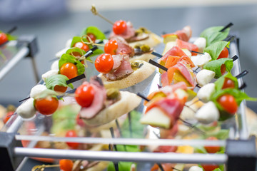Different canapes with smoked salmon, cucumber, tomatoes, cheese, meat. Breakfast buffet table with a variety of snacks. Buffet served table with snacks,fruits, canape, sweets and appetizers