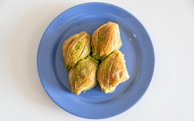 Turkish Midye Baklava ( Mussel Shaped Baklava ) with Green Pistachio Powder and Butter Cream. Turkish   baklava on blue dish