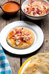 Salvadoran pupusas with coleslaw and tomato sauce on wooden background