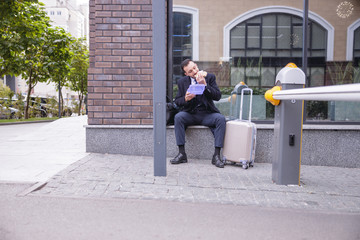 Hungry brunette man sitting near his suitcase