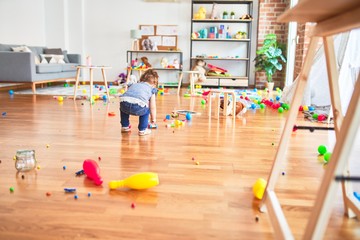 Beautiful toddler playing with train building with wooden blocks  at kindergarten