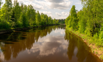 Fototapeta na wymiar summer landscape with river, green trees on shore and clouds, beautiful glare