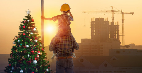 Asian boy on father's shoulders near Christmas tree with background of new high buildings and...