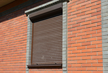 Rolling shutters brick house windows protection. Brick house with metal roller shutters on the windows