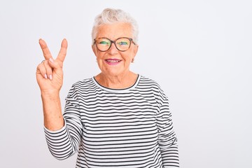 Senior grey-haired woman wearing striped navy t-shirt glasses over isolated white background showing and pointing up with fingers number two while smiling confident and happy.
