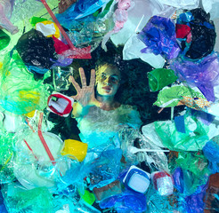 Woman drowning in water under plastic recipients pile, garbage. Used bottles and packs filling world ocean killing people. Ecology, environment concept, plastic and glass pollution, nature disaster.