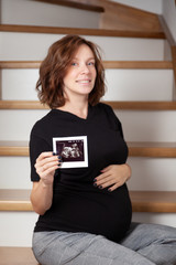 Pregnant woman looking at her baby sonography. Happy expectant lady enjoying first photo of her unborn child, anticipating her future life, copy space