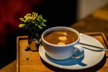 Kaffe schön angerichtet mit Blume auf Holzbrett