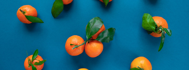 Fototapeta na wymiar Orange tangerine with leaves on an blue classic background
