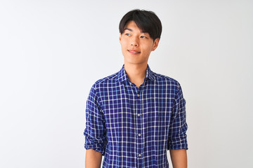 Young chinese man wearing casual blue shirt standing over isolated white background smiling looking to the side and staring away thinking.