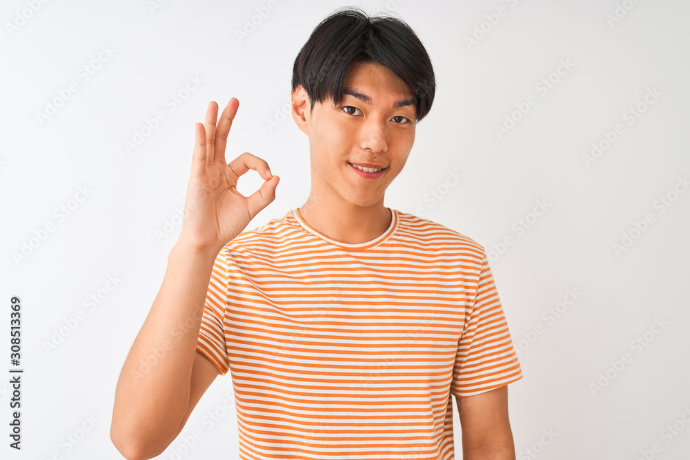 Poster Young chinese man wearing casual striped t-shirt standing over isolated white background smiling positive doing ok sign with hand and fingers. Successful expression.