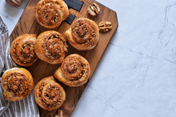 Snail buns with cinnamon and nuts on a concrete background.