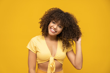 Happy laughing American African woman with her curly hair on yellow background. Laughing curly...